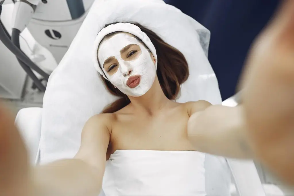 woman taking a selfie while having a facial treatment